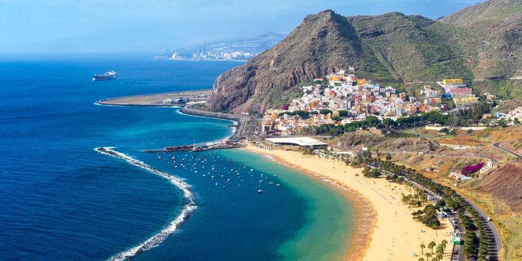 A panoramic view of a coastal town and golden beach in Tenerife, representing warm-weather accessible winter travel options for wheelchair users.